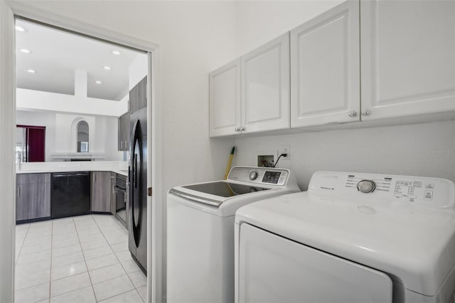 laundry room with separate washer and dryer, light tile patterned floors, and cabinets