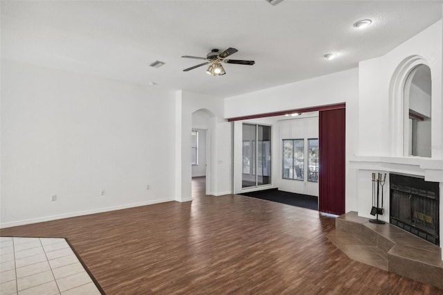 unfurnished living room with a fireplace, wood-type flooring, and ceiling fan