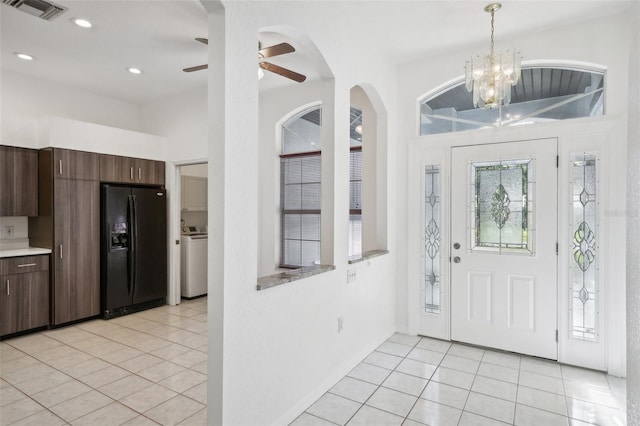 tiled foyer entrance with ceiling fan with notable chandelier and washer / clothes dryer