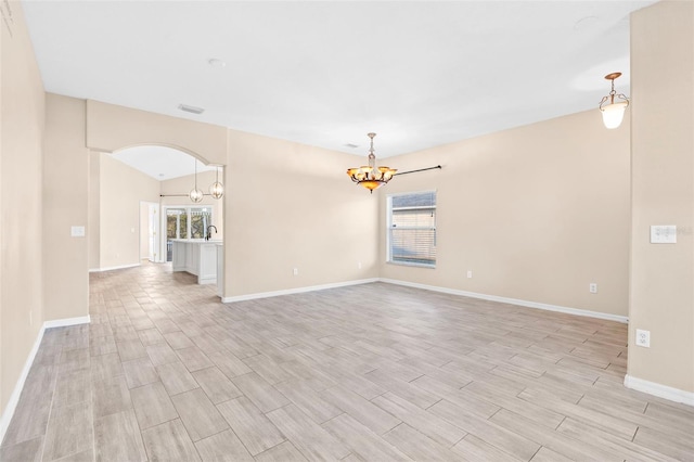 unfurnished room with a chandelier, light wood-type flooring, and vaulted ceiling