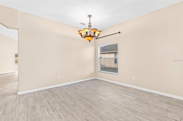 spare room featuring light hardwood / wood-style floors and a chandelier