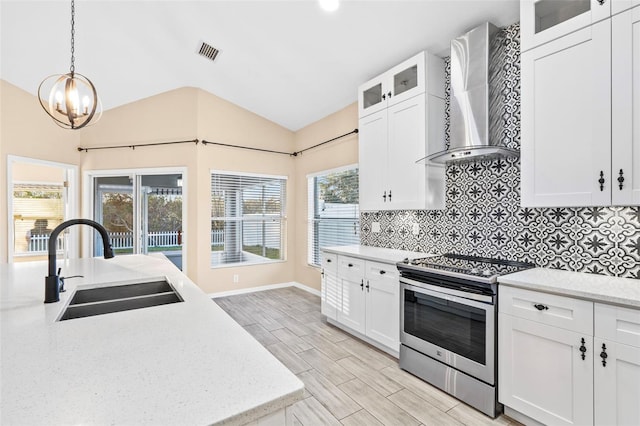 kitchen featuring stainless steel range with electric stovetop, vaulted ceiling, sink, wall chimney range hood, and white cabinets