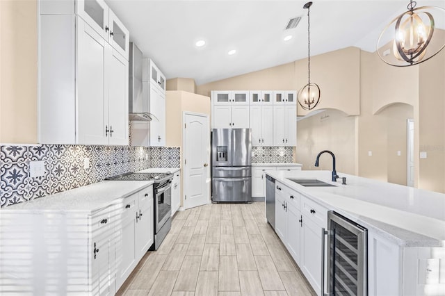 kitchen with appliances with stainless steel finishes, sink, decorative light fixtures, wine cooler, and lofted ceiling