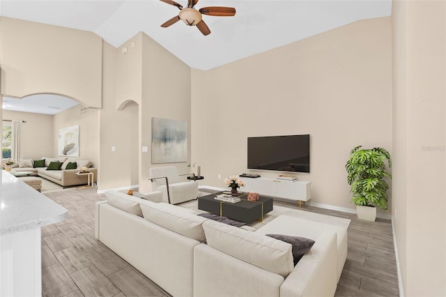 living room with ceiling fan, high vaulted ceiling, and light hardwood / wood-style floors