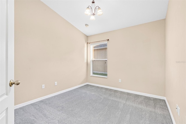 spare room with carpet floors, an inviting chandelier, and vaulted ceiling