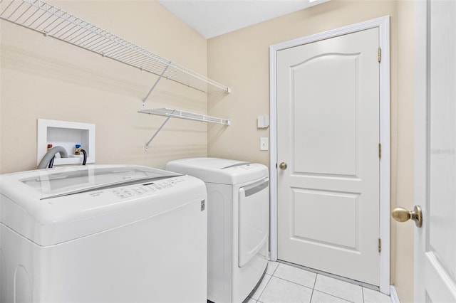 clothes washing area with washer and dryer and light tile patterned floors