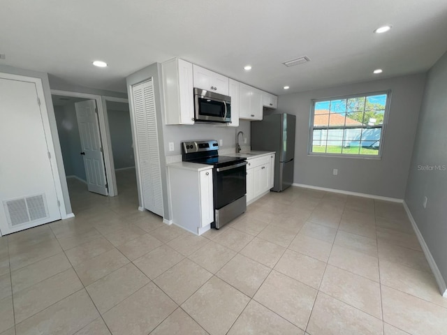 kitchen with sink, white cabinets, stainless steel appliances, and light tile patterned floors