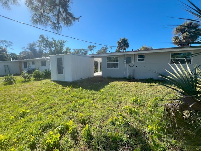 back of property featuring an outbuilding and a yard