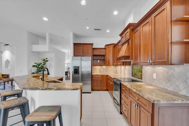 kitchen with a kitchen breakfast bar, sink, decorative backsplash, light stone counters, and stainless steel appliances