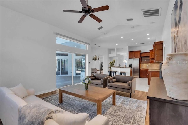 living room featuring ceiling fan with notable chandelier, light hardwood / wood-style floors, and lofted ceiling