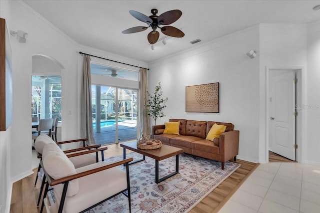 living room with light wood-type flooring, ceiling fan, and crown molding