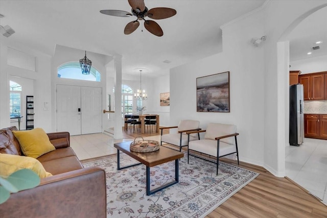 living room featuring ceiling fan with notable chandelier and light hardwood / wood-style floors