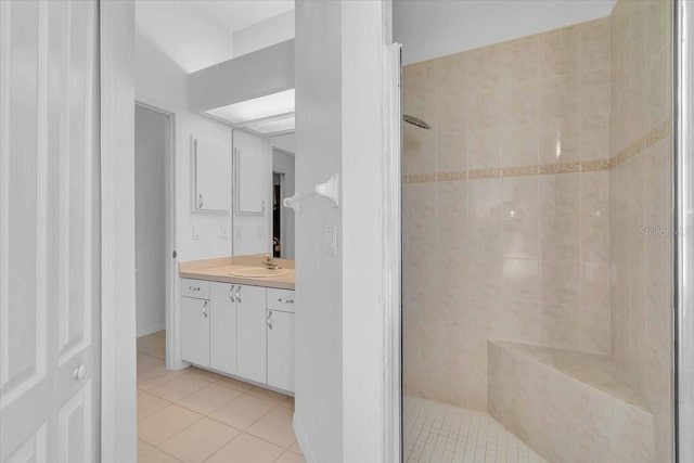 bathroom with a tile shower, vanity, and tile patterned floors