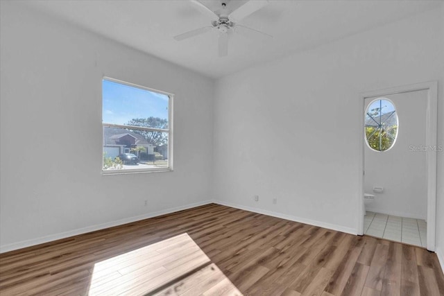 unfurnished room with hardwood / wood-style floors, ceiling fan, and a healthy amount of sunlight