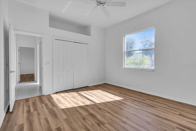 unfurnished bedroom featuring ceiling fan, light hardwood / wood-style floors, and a closet