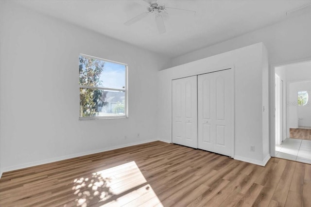 unfurnished bedroom with a closet, light hardwood / wood-style floors, multiple windows, and ceiling fan