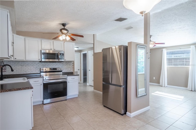 kitchen featuring lofted ceiling, backsplash, white cabinets, sink, and stainless steel appliances