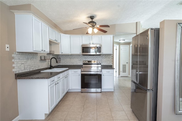 kitchen with sink, light tile patterned floors, decorative backsplash, white cabinets, and appliances with stainless steel finishes