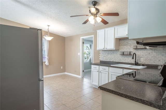 kitchen with stainless steel fridge, sink, white cabinets, and decorative light fixtures