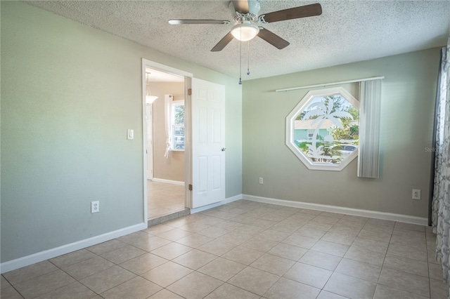 unfurnished room featuring ceiling fan, light tile patterned floors, and a textured ceiling