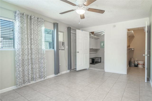 unfurnished bedroom featuring a textured ceiling, a walk in closet, a closet, and ceiling fan