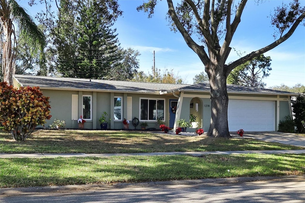 ranch-style home featuring a front lawn and a garage