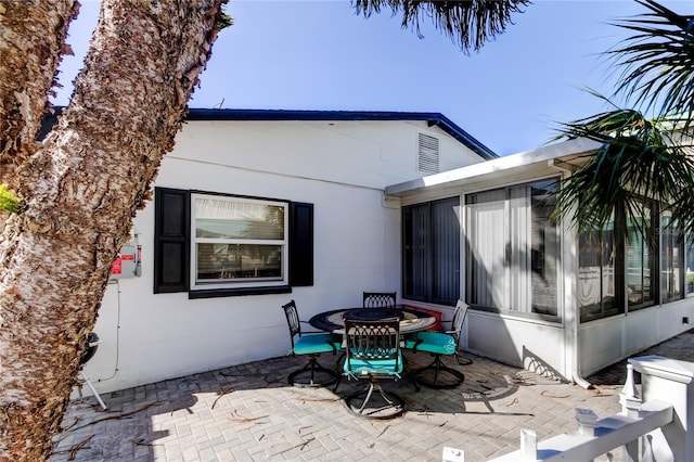 back of property featuring a sunroom, outdoor dining space, and a patio