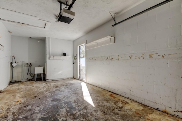 garage with a garage door opener, concrete block wall, and a sink