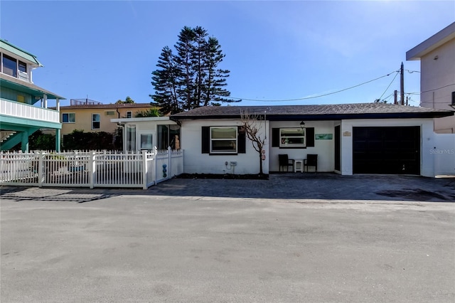 ranch-style house featuring a fenced front yard, an attached garage, and stucco siding