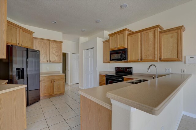 kitchen with kitchen peninsula, a textured ceiling, sink, black appliances, and light tile patterned floors