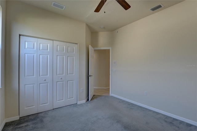 unfurnished bedroom featuring ceiling fan, a closet, and light colored carpet