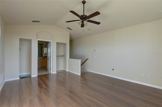 spare room with ceiling fan, built in features, dark wood-type flooring, and vaulted ceiling