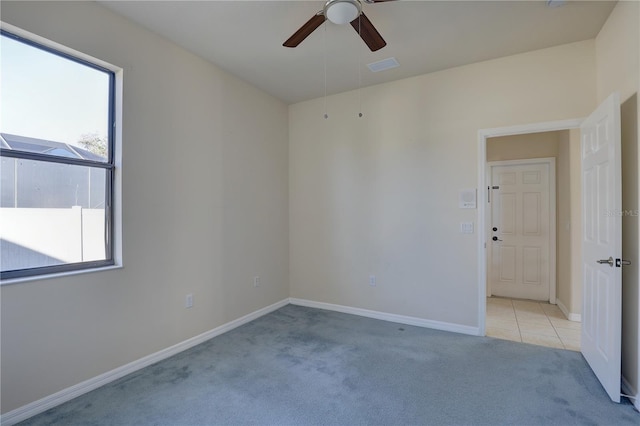 empty room with light colored carpet, a wealth of natural light, and ceiling fan