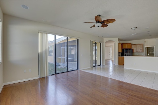 unfurnished living room with light hardwood / wood-style flooring, ceiling fan, and sink