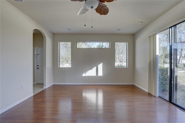 unfurnished room with wood-type flooring, a textured ceiling, and plenty of natural light