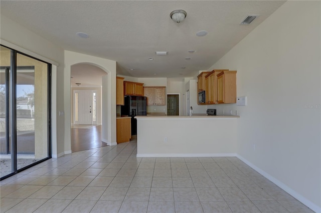 kitchen with kitchen peninsula, plenty of natural light, black appliances, and a textured ceiling