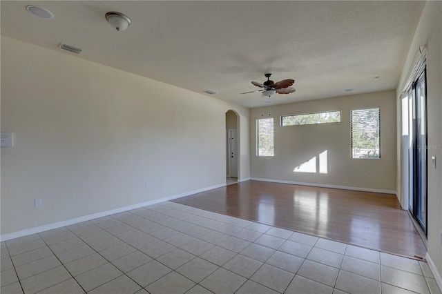 unfurnished room with ceiling fan, a healthy amount of sunlight, a textured ceiling, and light wood-type flooring