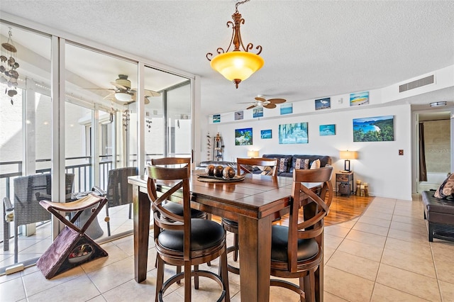 tiled dining area featuring plenty of natural light, expansive windows, and a textured ceiling