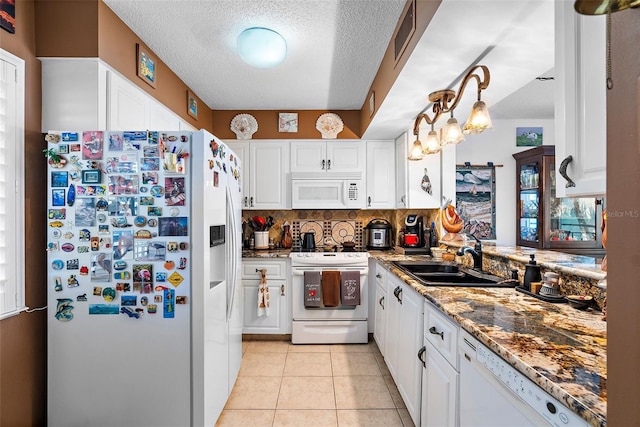 kitchen with sink, tasteful backsplash, decorative light fixtures, white appliances, and white cabinets