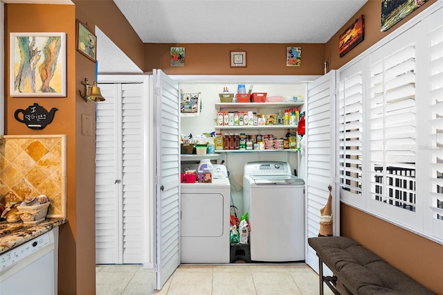 washroom featuring separate washer and dryer, light tile patterned floors, and a textured ceiling