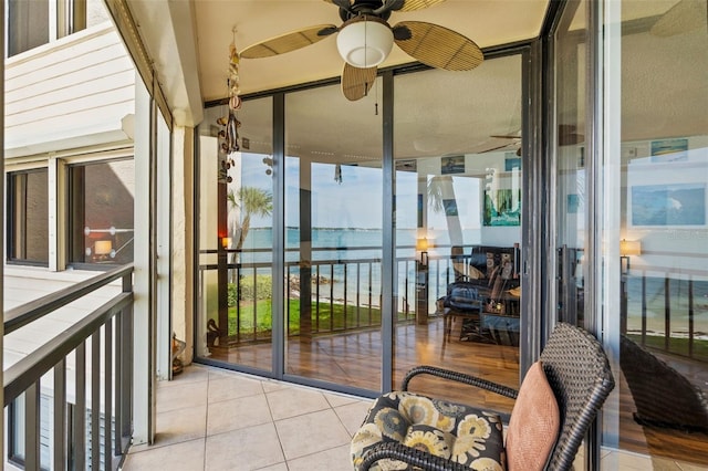 sunroom featuring ceiling fan and a water view