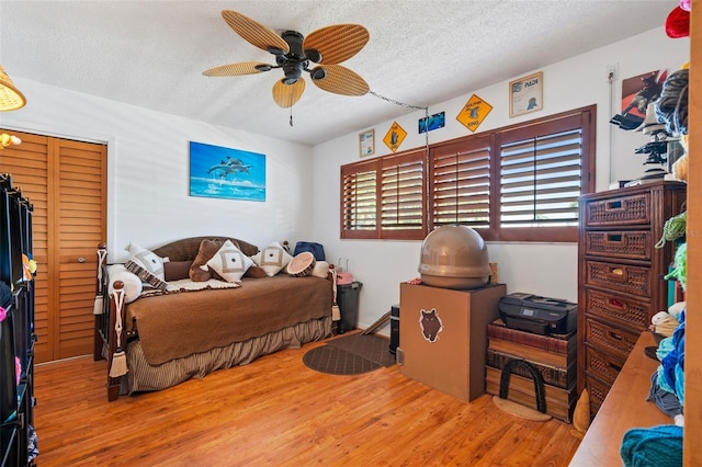 bedroom featuring ceiling fan, wood-type flooring, and a textured ceiling