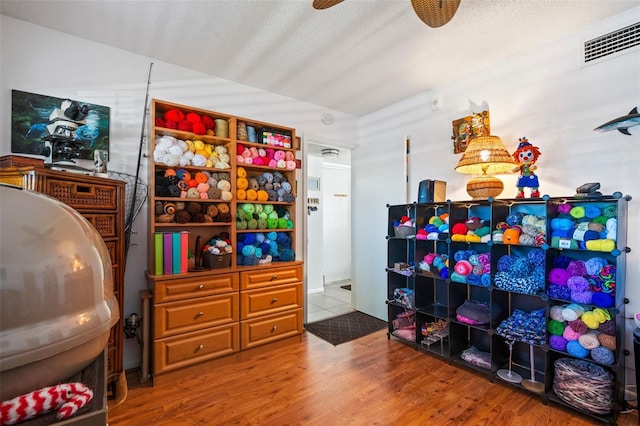 playroom featuring hardwood / wood-style floors, ceiling fan, and a textured ceiling