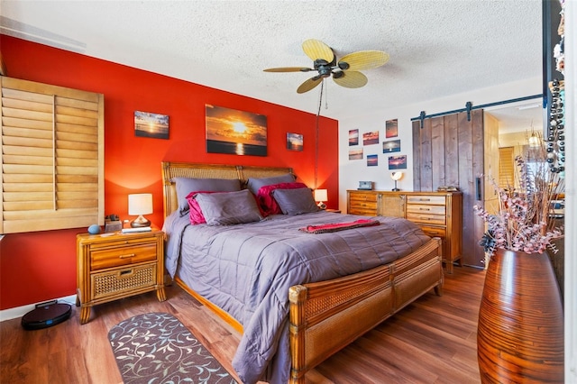 bedroom with hardwood / wood-style flooring, ceiling fan, a barn door, and a textured ceiling