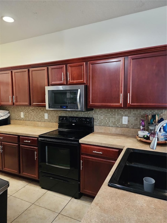 kitchen featuring black / electric stove, decorative backsplash, sink, and light tile patterned floors