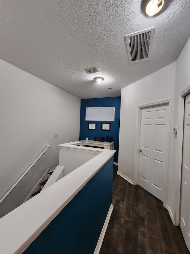 hallway featuring a textured ceiling and dark wood-type flooring