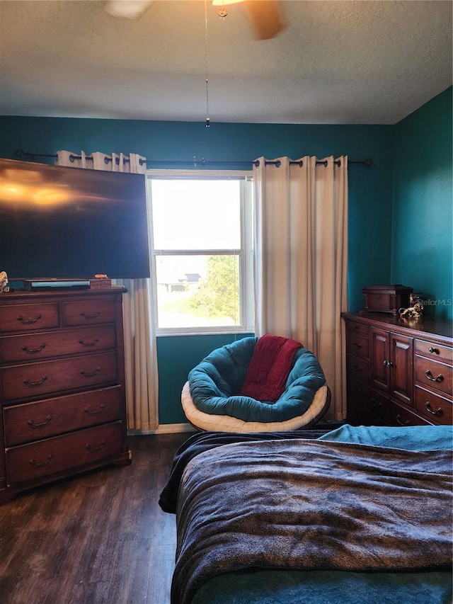 bedroom with ceiling fan, dark hardwood / wood-style flooring, and a textured ceiling