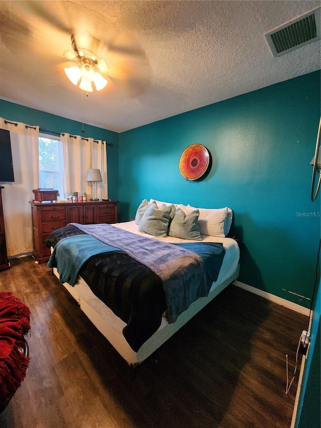 bedroom with ceiling fan, dark hardwood / wood-style flooring, and a textured ceiling