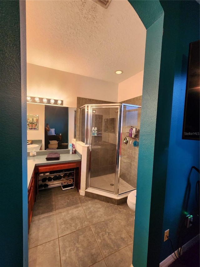 bathroom with tile patterned flooring, vanity, an enclosed shower, and toilet