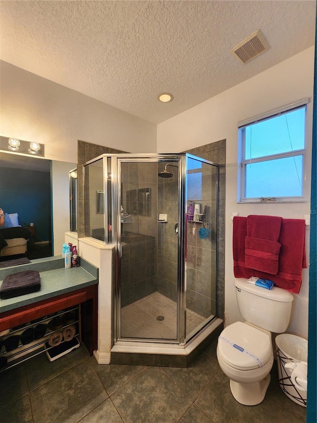 bathroom with toilet, a textured ceiling, tile patterned floors, and a shower with shower door